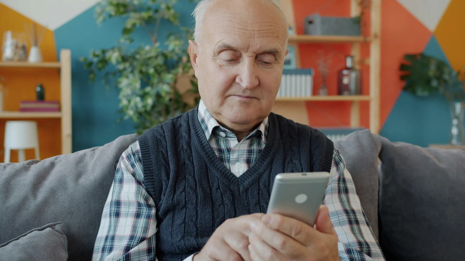 Pessoa idosa usando smartphone em casa, representando consulta segura de descontos associativos no benefício do INSS sem dados pessoais visíveis